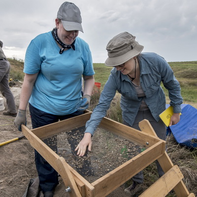 An anthropology student sifts dirt in the field